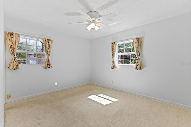 carpeted empty room featuring ceiling fan and baseboards