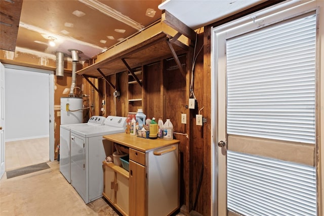 clothes washing area with water heater, wood walls, and separate washer and dryer