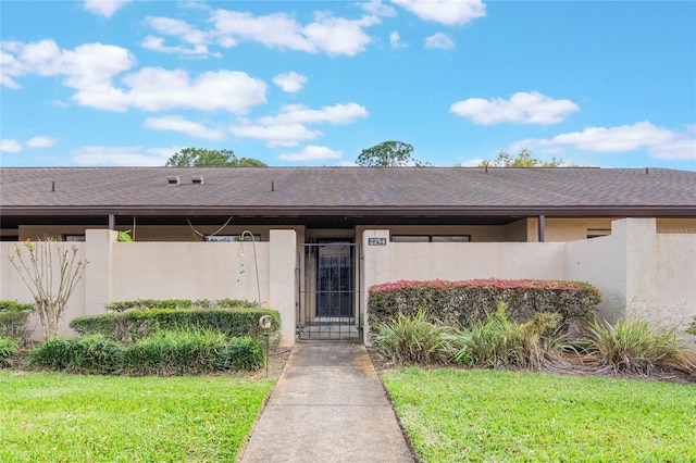 property entrance with a shingled roof, a gate, fence, and stucco siding