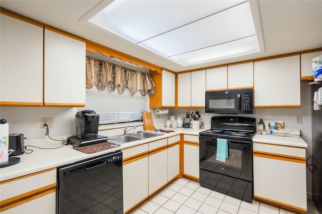 kitchen featuring white cabinets, light countertops, a sink, and black appliances