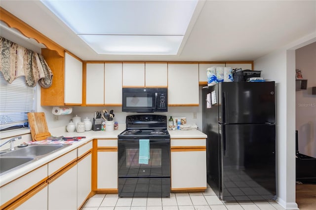 kitchen with white cabinets, light countertops, a sink, and black appliances