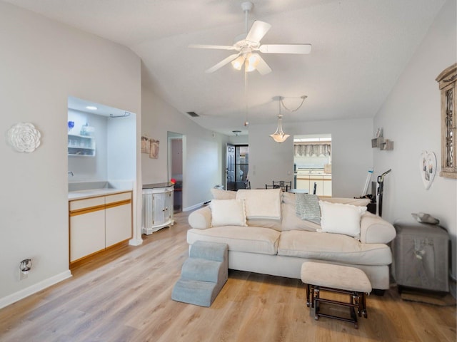 living area with vaulted ceiling, light wood-style flooring, baseboards, and ceiling fan