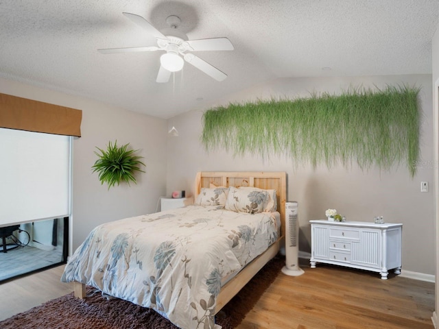 bedroom with a ceiling fan, lofted ceiling, a textured ceiling, and wood finished floors