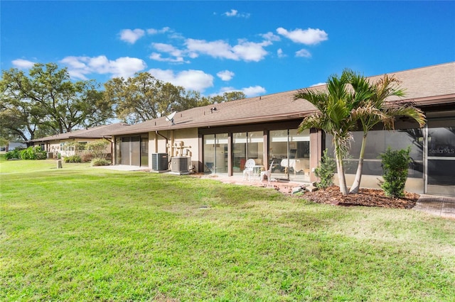 rear view of house featuring central AC, a lawn, a patio, and a sunroom