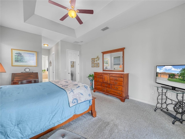 carpeted bedroom featuring a tray ceiling, visible vents, ceiling fan, and baseboards