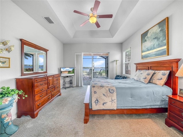 bedroom featuring visible vents, a raised ceiling, a ceiling fan, access to outside, and carpet floors