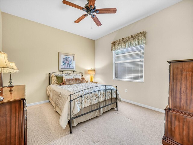 bedroom with light carpet, ceiling fan, and baseboards