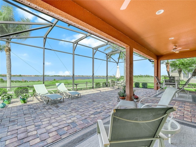 view of patio / terrace featuring glass enclosure, a ceiling fan, and outdoor dining space