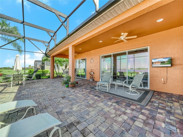 view of patio featuring outdoor dining area, glass enclosure, and ceiling fan