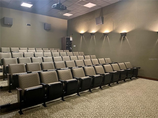 carpeted cinema featuring a paneled ceiling and baseboards