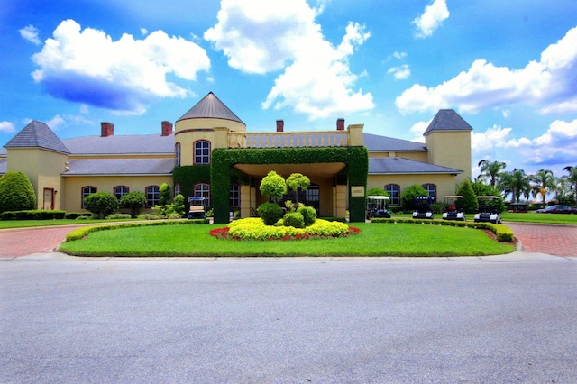 view of front of house featuring a front lawn, decorative driveway, a chimney, and stucco siding