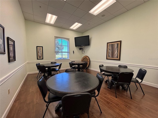 dining area featuring a paneled ceiling, baseboards, and dark wood-style flooring