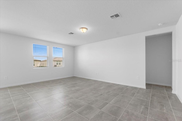 unfurnished room featuring a textured ceiling, visible vents, and baseboards