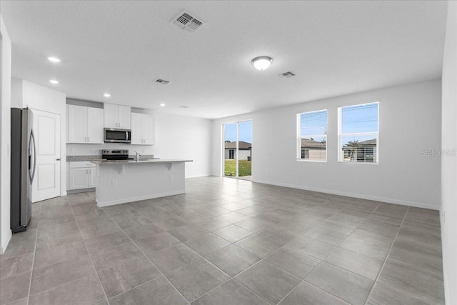 kitchen with stainless steel appliances, open floor plan, visible vents, and white cabinetry