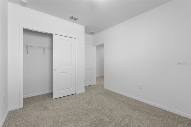 unfurnished bedroom with carpet floors, a closet, visible vents, and a textured ceiling