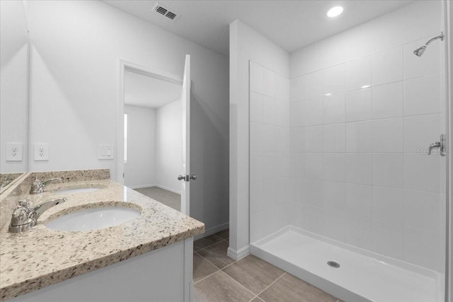 bathroom featuring visible vents, a sink, a tile shower, and tile patterned floors