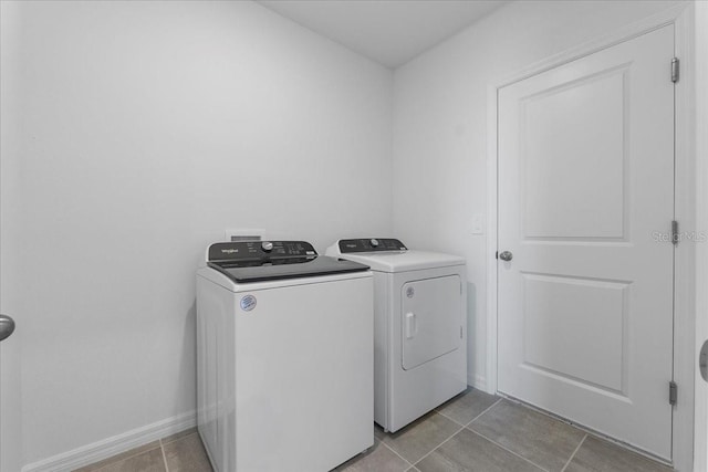 laundry room with light tile patterned floors, laundry area, separate washer and dryer, and baseboards