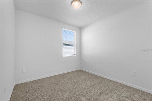 carpeted spare room featuring baseboards