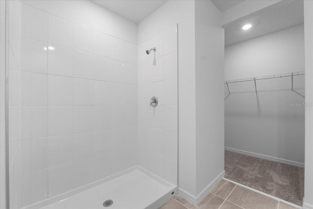 bathroom with baseboards, a spacious closet, a stall shower, and tile patterned floors