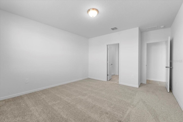 unfurnished bedroom featuring baseboards, visible vents, and light colored carpet