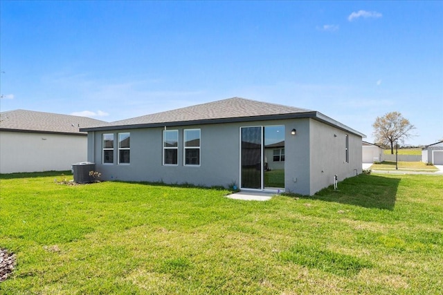 rear view of property featuring central air condition unit, a lawn, and stucco siding