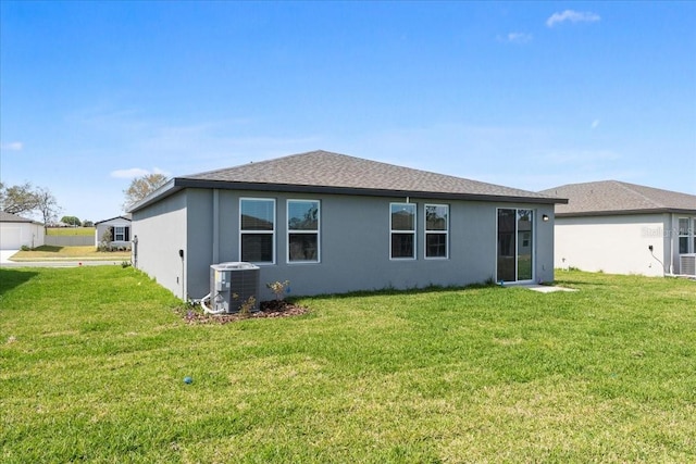 rear view of property with central AC, a lawn, and stucco siding