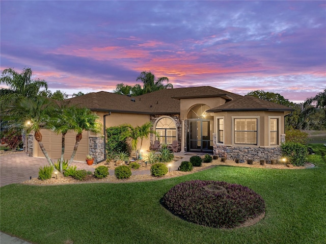 view of front of house featuring an attached garage, roof with shingles, decorative driveway, stucco siding, and a front lawn