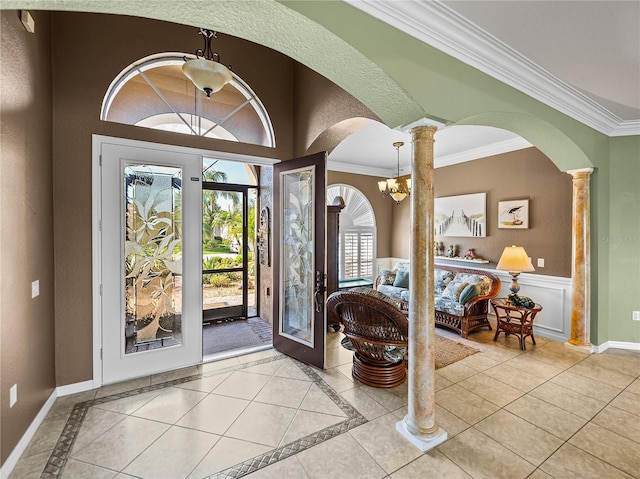 foyer entrance with ornate columns, light tile patterned floors, baseboards, and crown molding