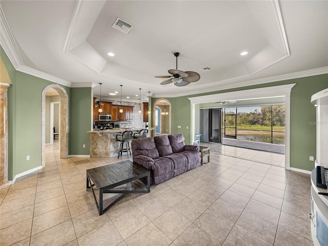 living room featuring arched walkways, a tray ceiling, light tile patterned floors, and visible vents