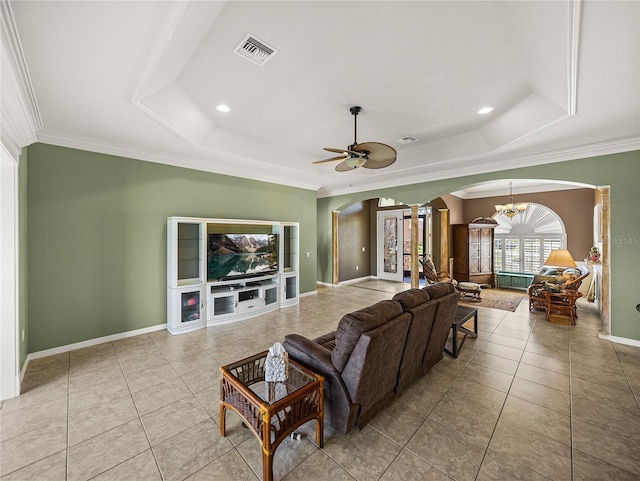 tiled living room with arched walkways, visible vents, crown molding, and a tray ceiling