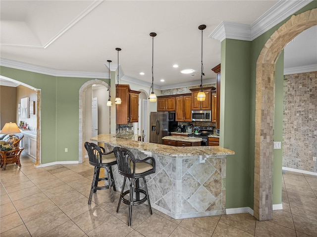 kitchen with arched walkways, stainless steel appliances, brown cabinetry, and crown molding