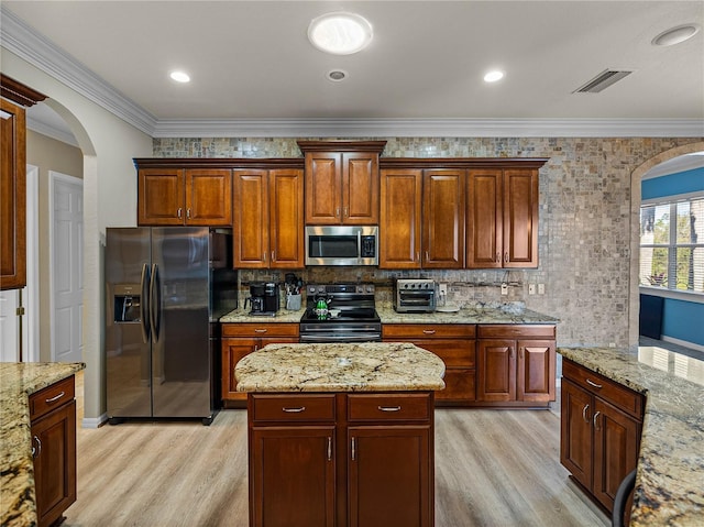 kitchen with light wood finished floors, visible vents, stainless steel appliances, and decorative backsplash