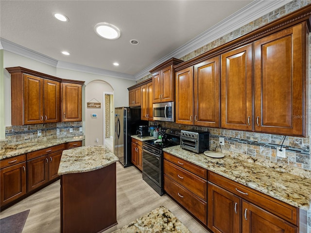 kitchen with arched walkways, range with two ovens, stainless steel microwave, ornamental molding, and freestanding refrigerator