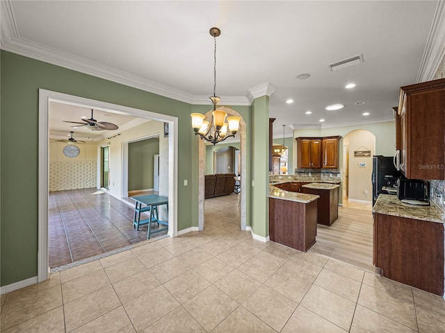 kitchen featuring light stone counters, arched walkways, visible vents, freestanding refrigerator, and light tile patterned flooring