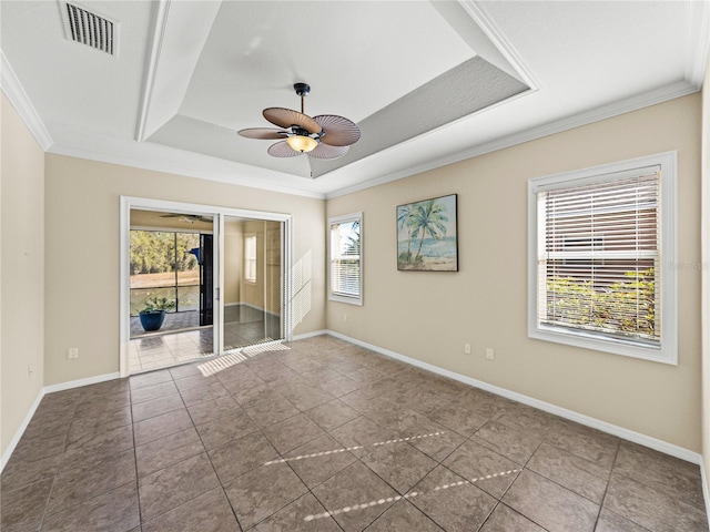 spare room with a raised ceiling, visible vents, ornamental molding, a ceiling fan, and baseboards