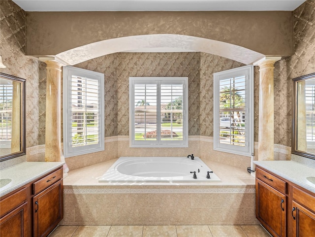 bathroom with a garden tub, decorative columns, tile patterned floors, and vanity