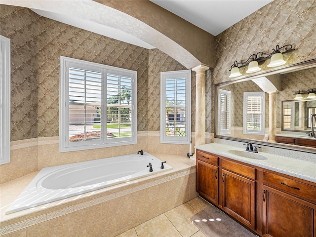 bathroom with tile patterned flooring, vanity, a bath, decorative columns, and wallpapered walls