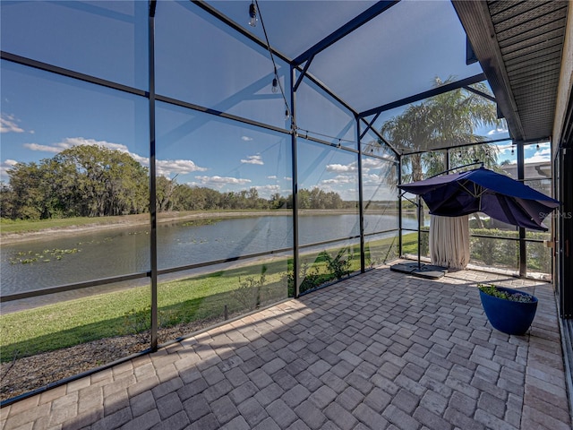 view of patio featuring glass enclosure and a water view