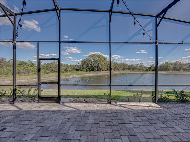 view of patio / terrace featuring a lanai and a water view