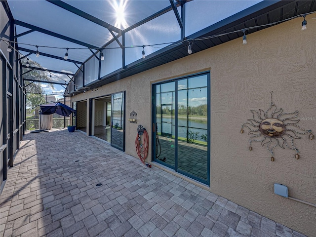 view of patio with a water view and a lanai