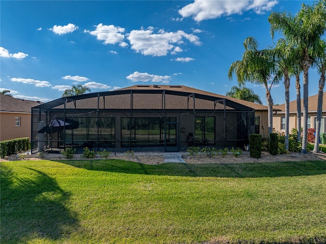 rear view of property with glass enclosure and a lawn