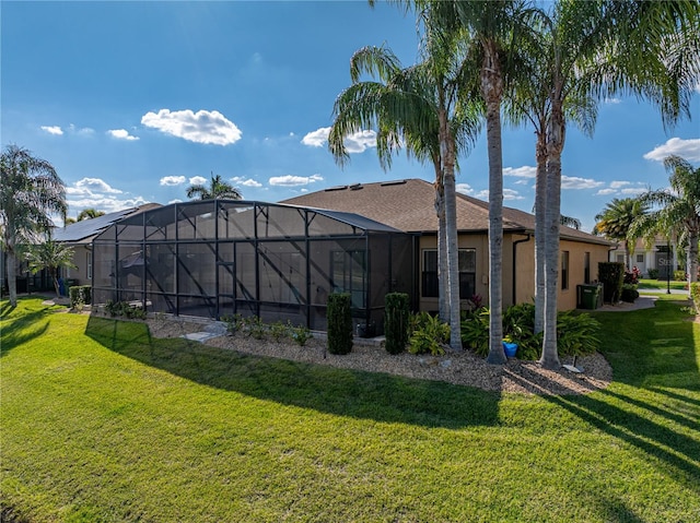 rear view of property with a lanai, a yard, and stucco siding