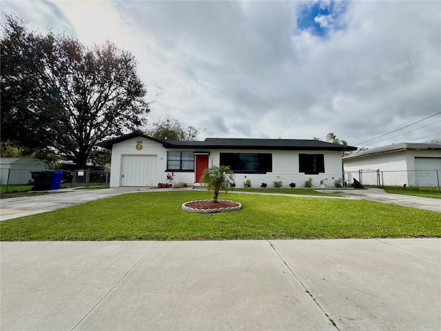 ranch-style house featuring an attached garage, fence, concrete driveway, and a front yard