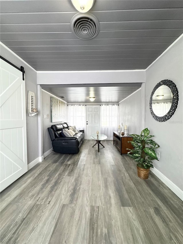 unfurnished room featuring ornamental molding, wood finished floors, visible vents, and a barn door