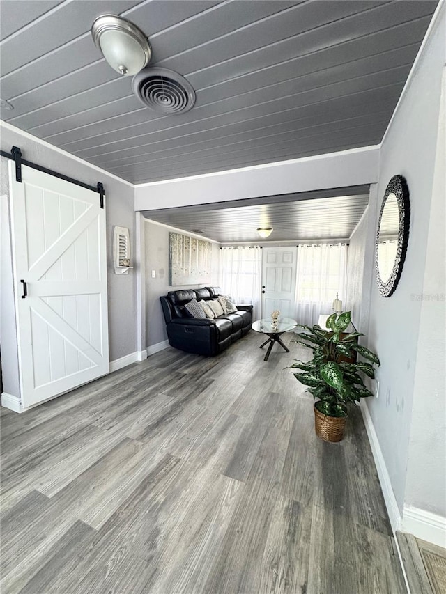 interior space featuring baseboards, a barn door, visible vents, and wood finished floors