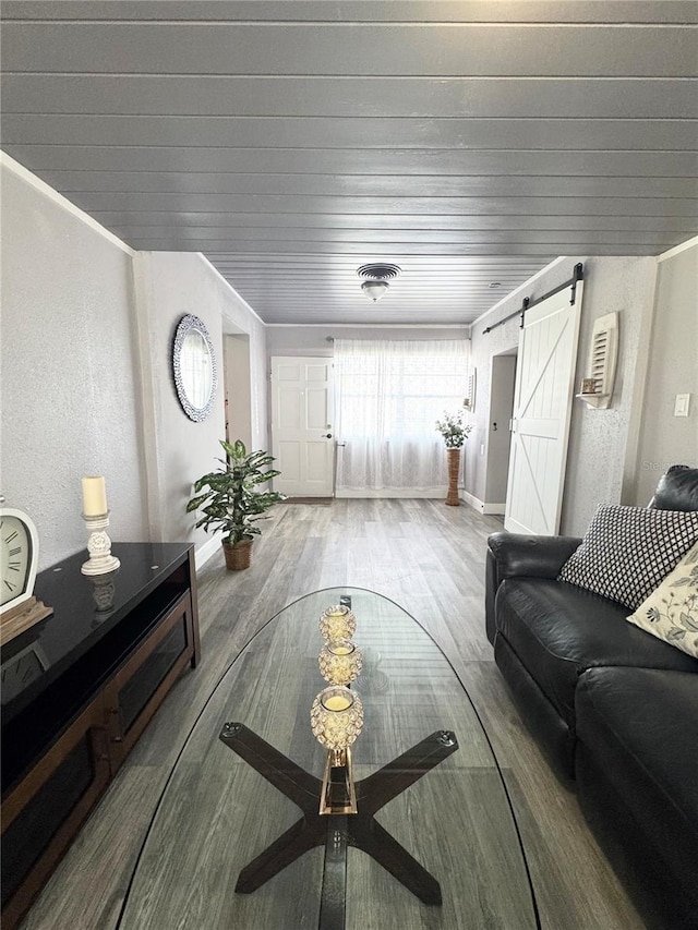 living room featuring a barn door, baseboards, wood finished floors, and a textured wall