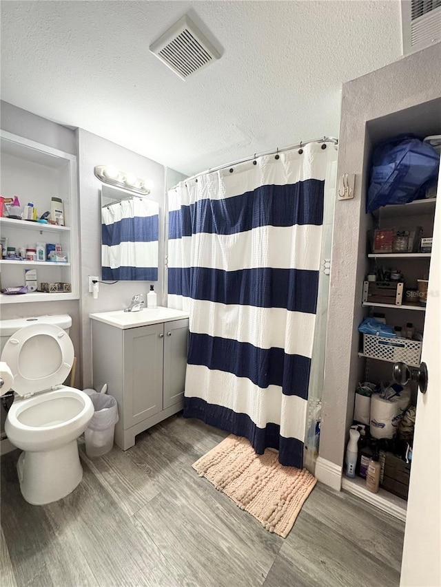 full bathroom featuring a textured ceiling, wood finished floors, vanity, visible vents, and a shower with curtain