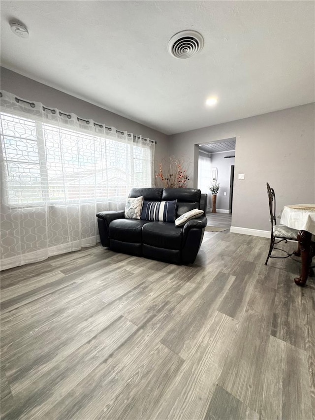 living room with baseboards, visible vents, and wood finished floors