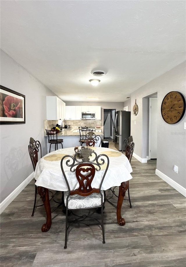 dining area with baseboards, visible vents, and wood finished floors