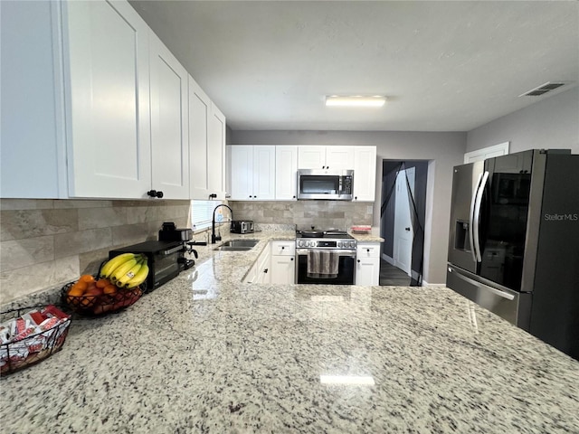 kitchen with tasteful backsplash, visible vents, appliances with stainless steel finishes, a sink, and light stone countertops